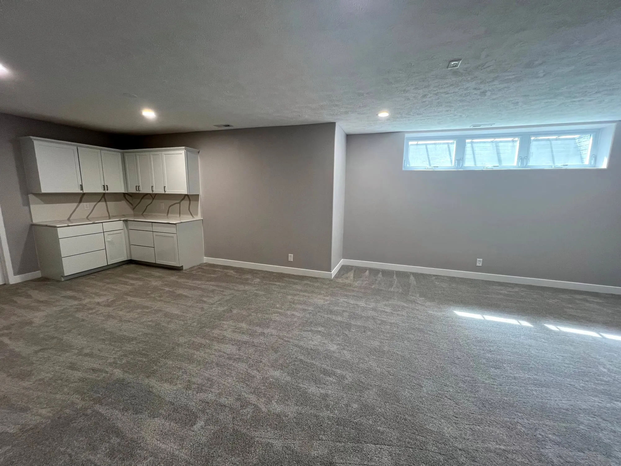 Finished basement with new carpet and wet bar cabinets