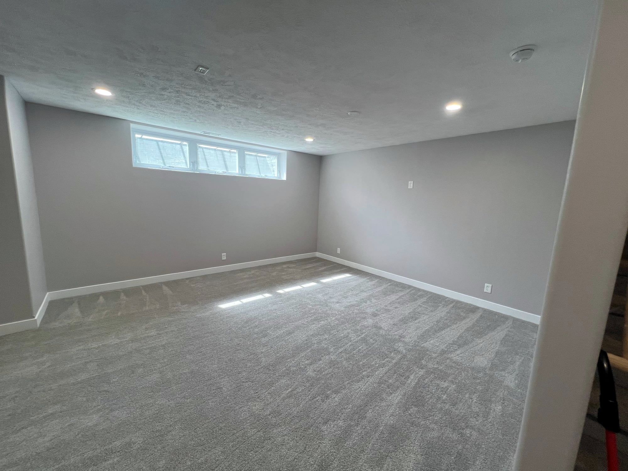 The same basement finished with paint, carpet and recessed lights
