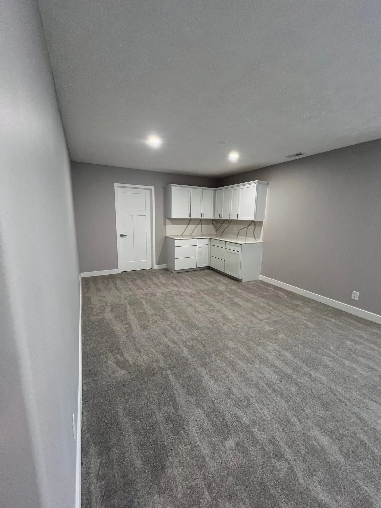 Finished basement room with kitchenette cabinets