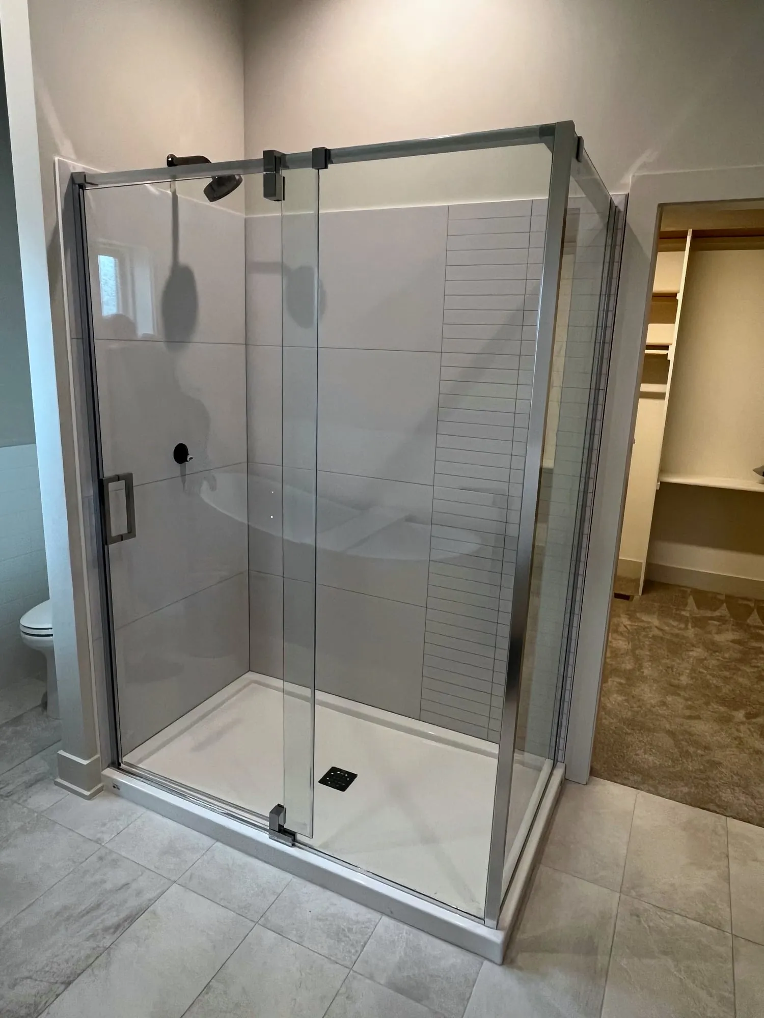 Walk-in shower with frameless glass and large gray tile