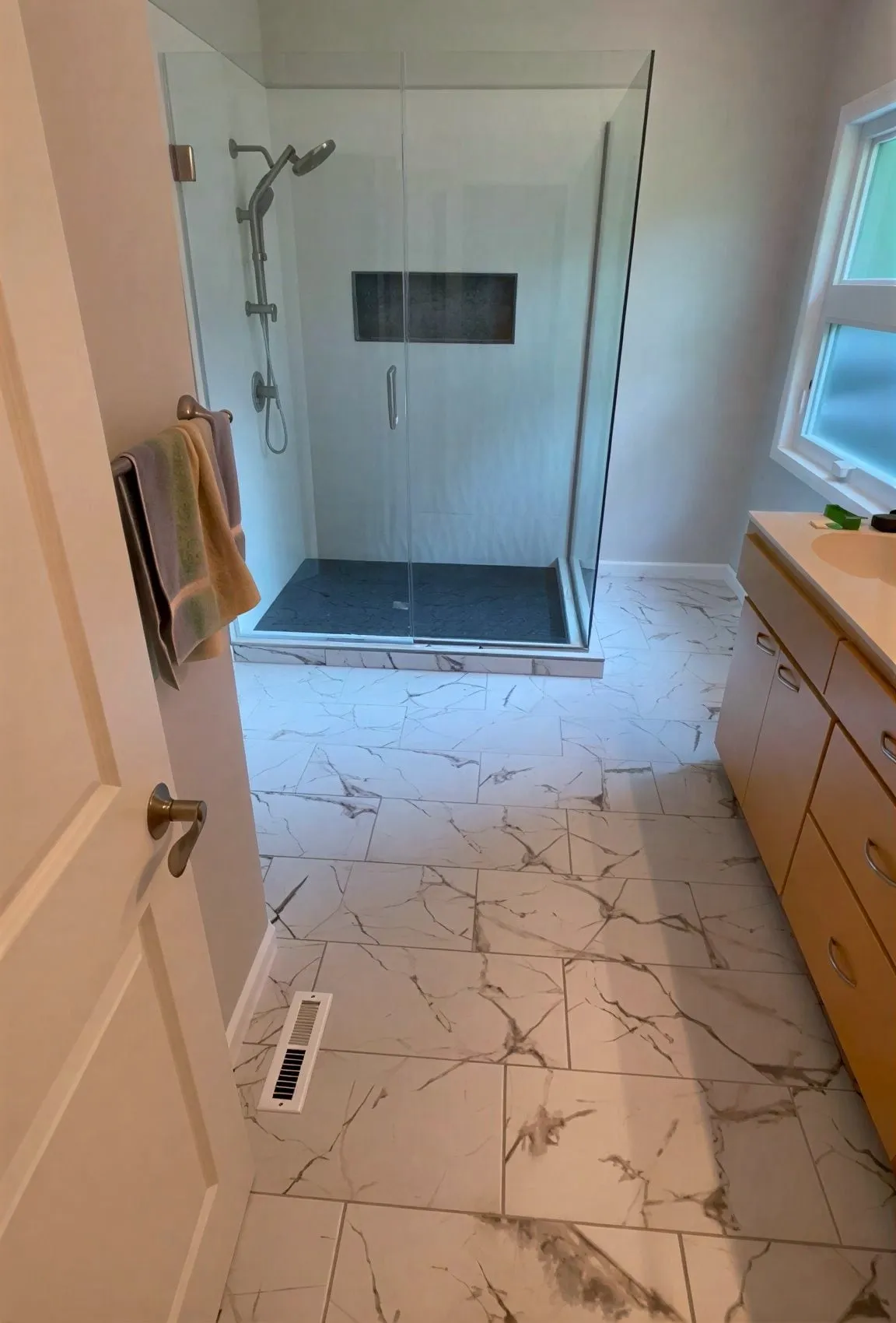 Walk-in shower with marble-look tile and a glass panel