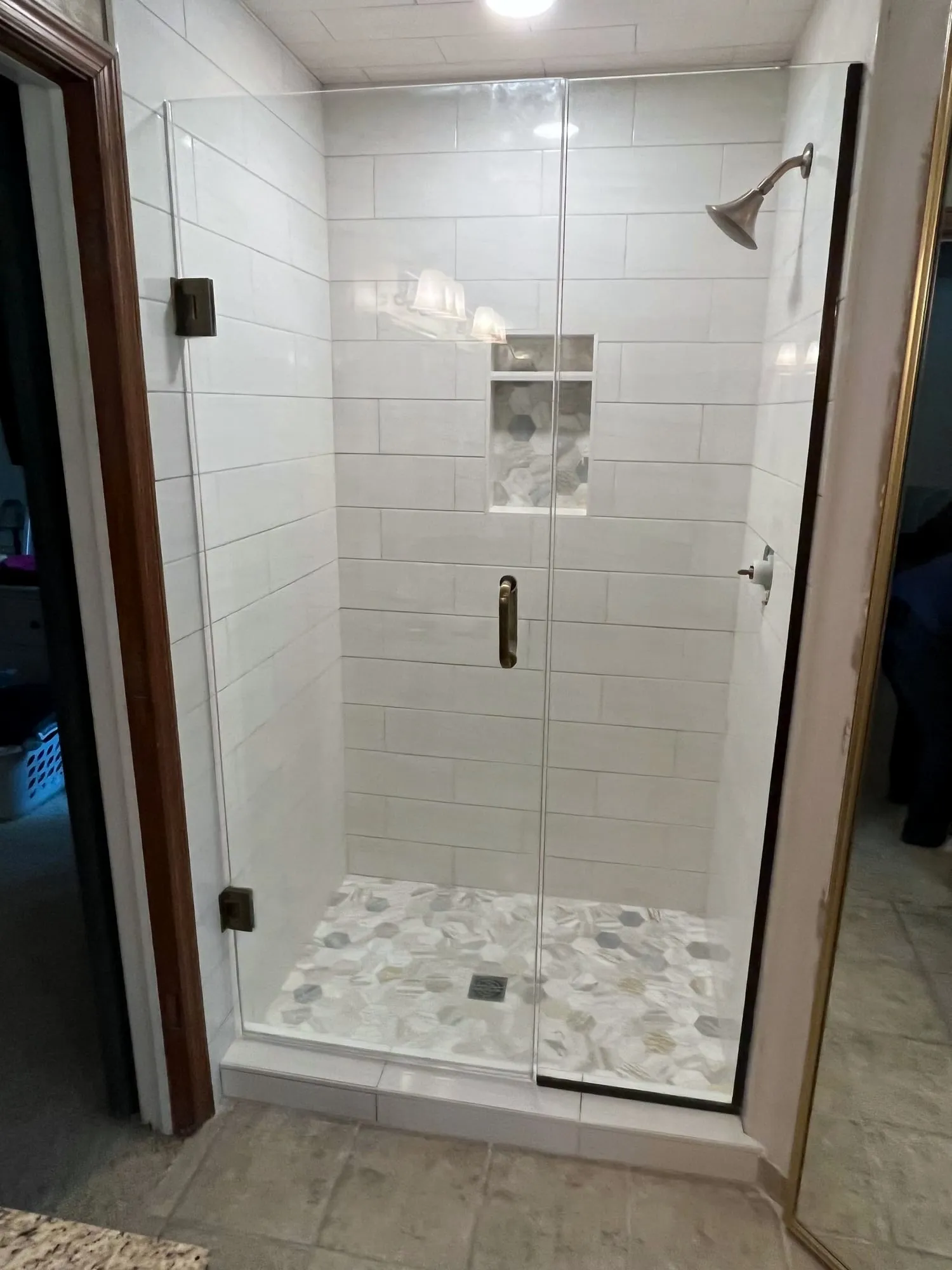 Subway tile shower with a glass door and pebble floor