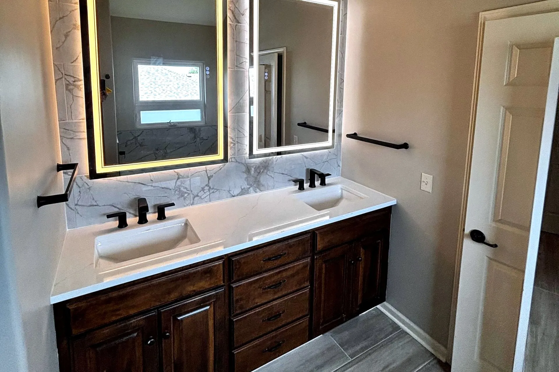 Double vanity with backlit mirrors and black faucets