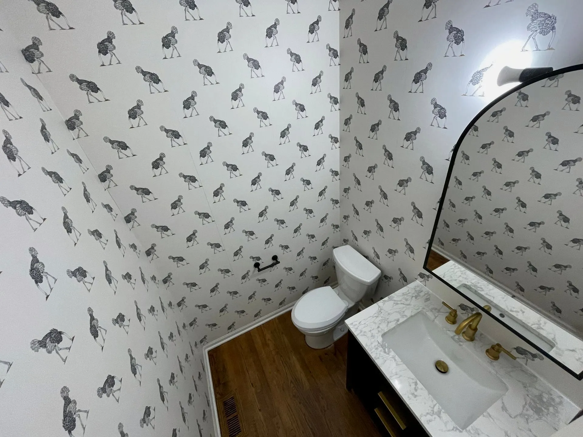 Powder room with patterned wallpaper and a marble vanity