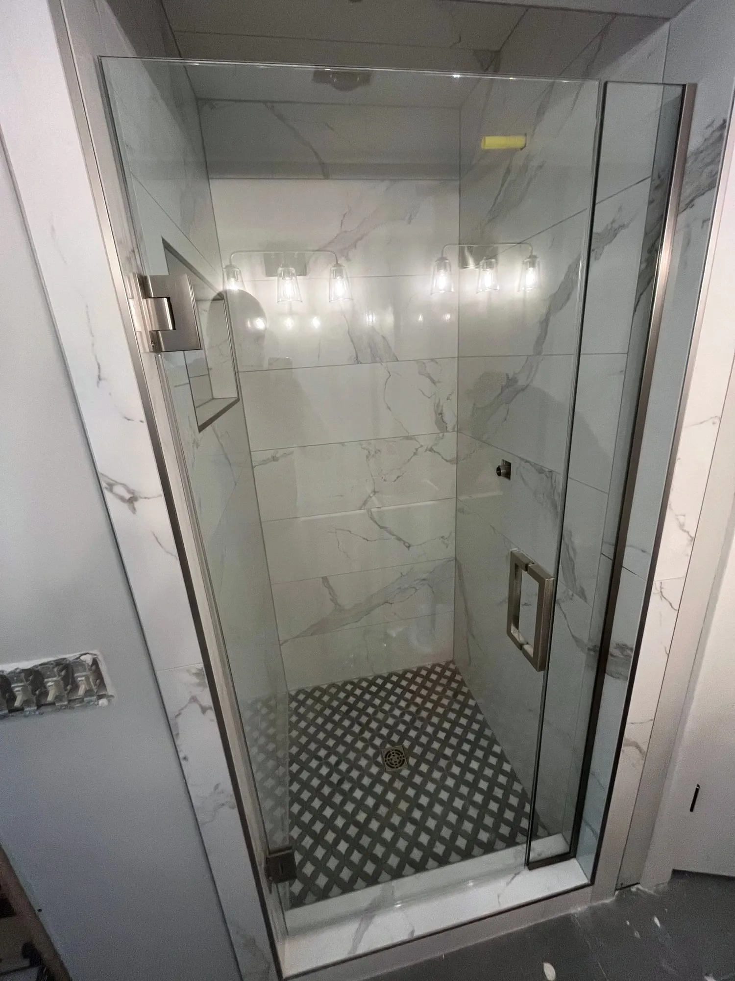 Glass shower with marble-look tile and a hex floor