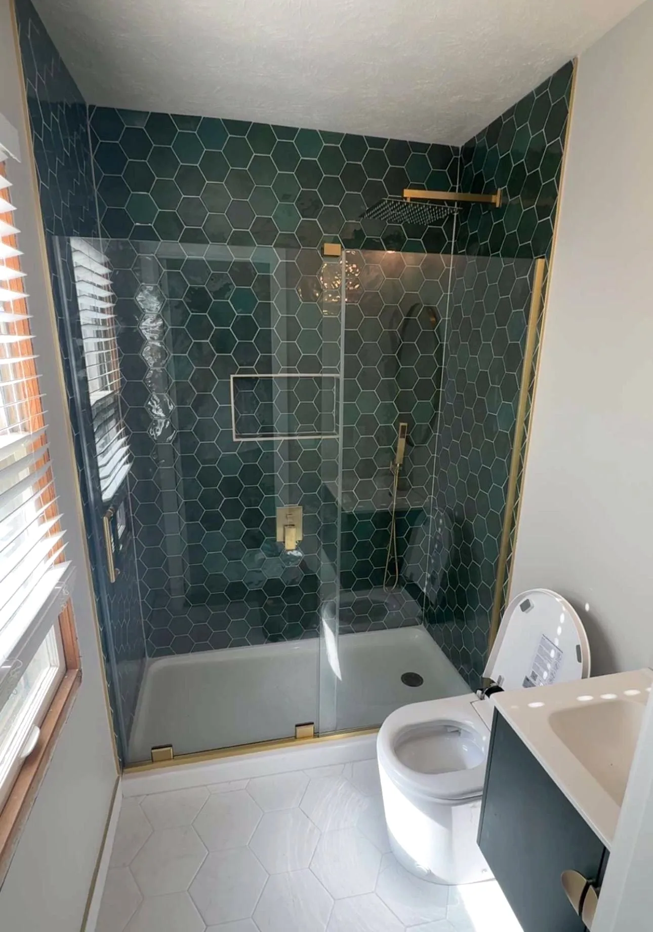 Shower with green hex tile and gold fixtures