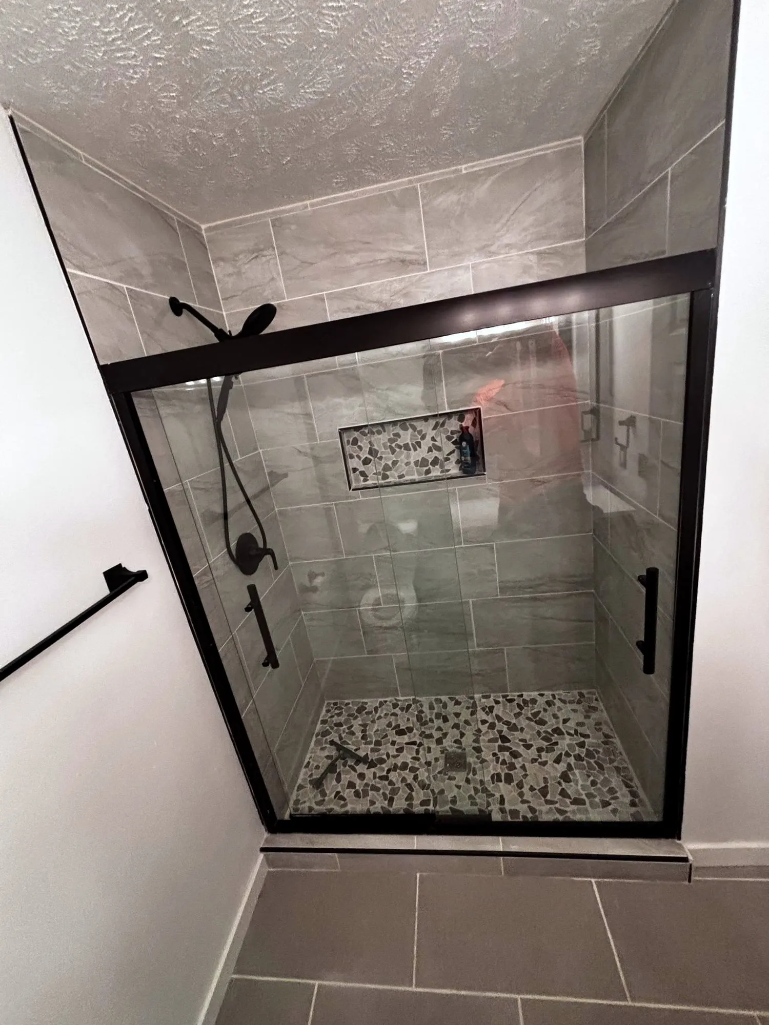 Shower with black-framed glass and a pebble floor