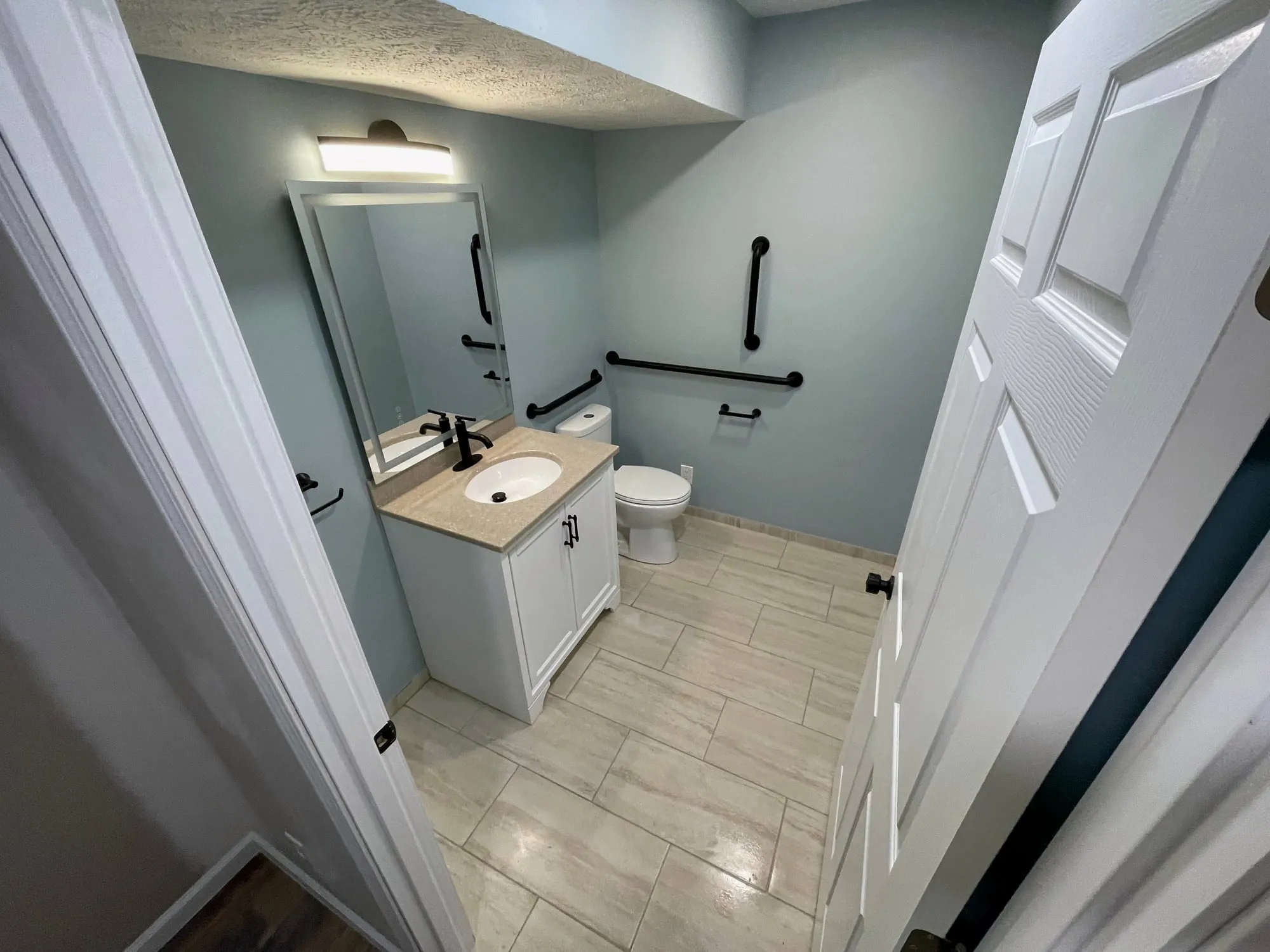 Accessible bathroom vanity with a lighted mirror and grab bars