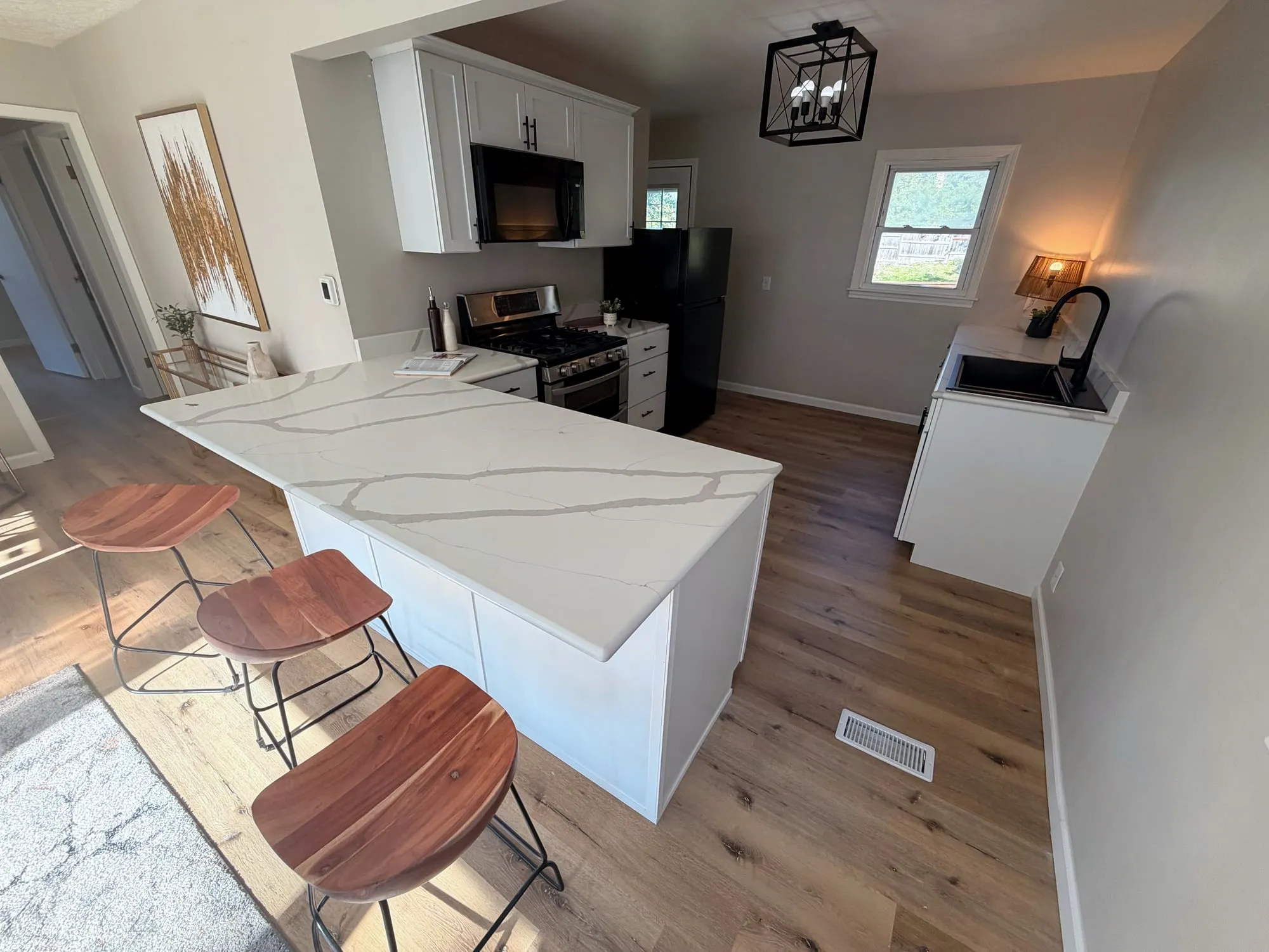 Remodeled kitchen with white cabinets and a quartz peninsula