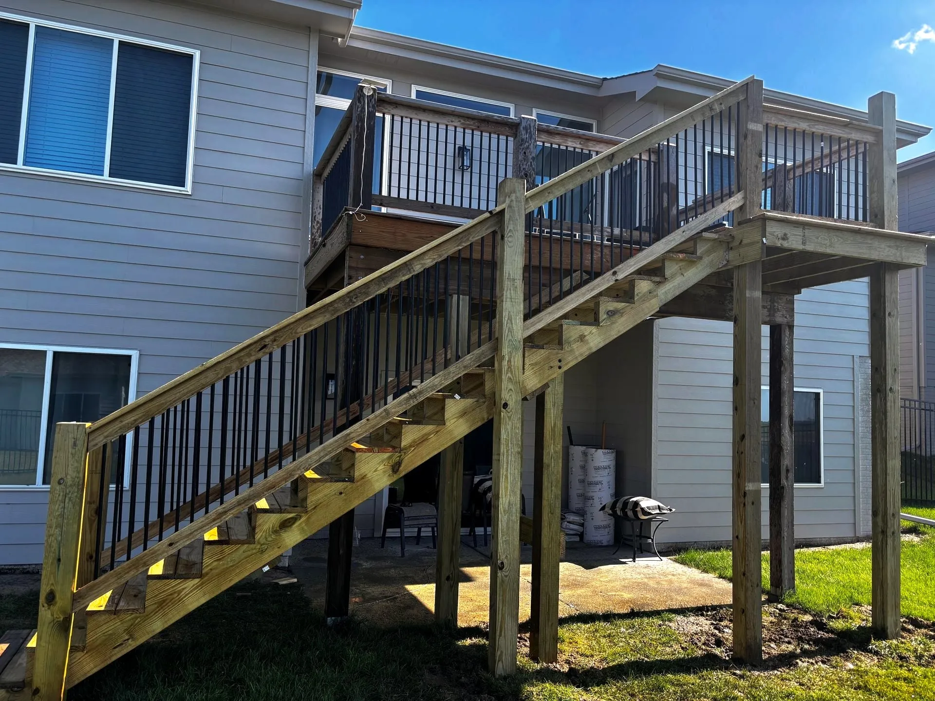 Deck stairs up to an upper deck with a black railing
