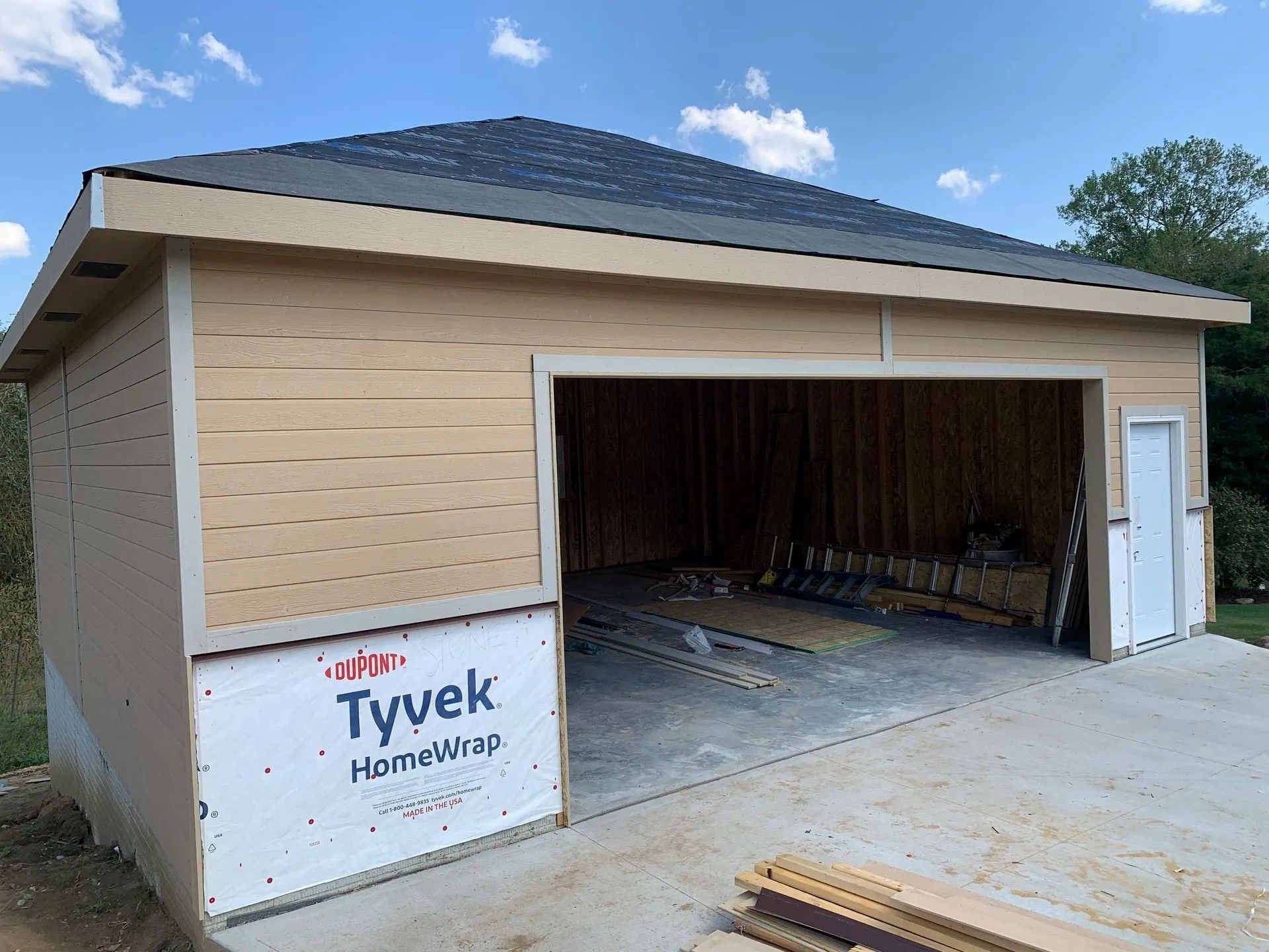 Detached garage with siding going on over house wrap